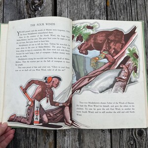 K&ouml;nnte beinhalten: Ein aufgeschlagenes Vintage-M&auml;rchenbuch mit dem Titel The Four Winds mit gedrucktem Text und farbigen Illustrationen. Die linke Seite zeigt einen Krieger mit einer Keule, w&auml;hrend die rechte Seite einen Braunb&auml;ren auf einem Ast darstellt.