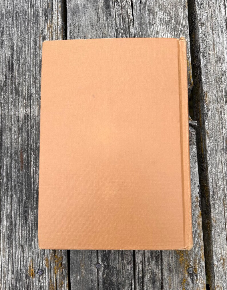 K&ouml;nnte beinhalten: Ein rechteckiges Hardcover-Buch mit einem einfarbigen, hellbraunen oder beigen Stoffeinband. Das Buch ist vertikal ausgerichtet und zeigt den Vorderdeckel sowie die Buchr&uuml;cken-Kante auf der rechten Seite mit einer schlichten Oberfl&auml;che.