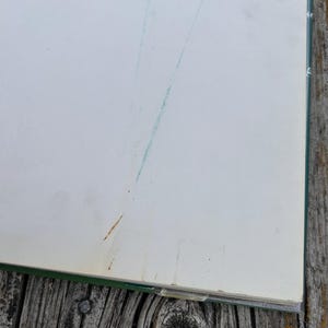 Peut inclure: Un livre &agrave; couverture vert fonc&eacute; avec des pages blanc cass&eacute;. La page ouverte pr&eacute;sente une fine ligne diagonale bleu sarcelle trac&eacute;e &agrave; l'encre ou au crayon, ainsi qu'une petite tache brun clair pr&egrave;s du coin inf&eacute;rieur gauche de la page.