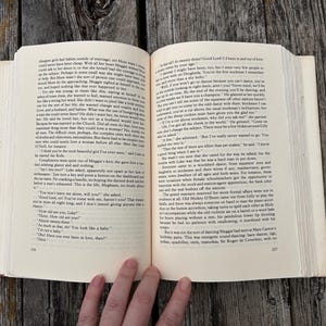 May include: An open hardcover book with cream-colored pages featuring black printed text. The left page is numbered 226 and the right page is numbered 227. The book is held open, displaying two full columns of narrative text in a serif font.