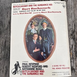 K&ouml;nnte beinhalten: Ein Notenbuch f&uuml;r Klavier und Gesang zum Film Butch Cassidy und Sundance Kid von Burt Bacharach. Das Cover zeigt ein zentrales ovales Foto von Paul Newman, Robert Redford und Katharine Ross in historischer Kleidung.