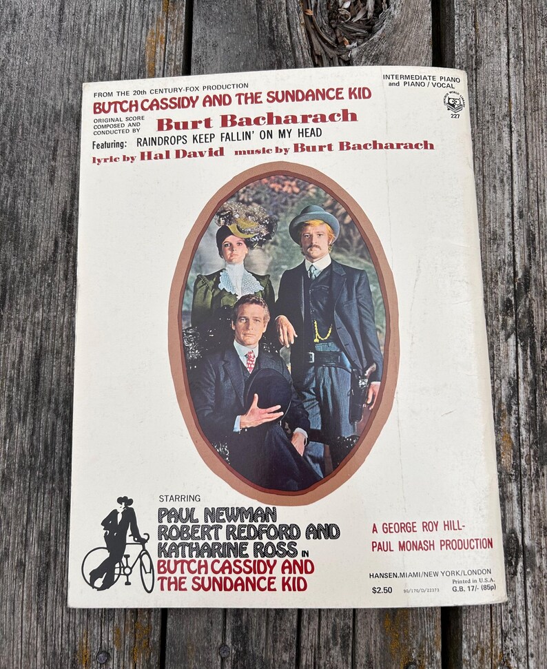 K&ouml;nnte beinhalten: Ein Notenbuch f&uuml;r Klavier und Gesang zum Film Butch Cassidy und Sundance Kid von Burt Bacharach. Das Cover zeigt ein zentrales ovales Foto von Paul Newman, Robert Redford und Katharine Ross in historischer Kleidung.