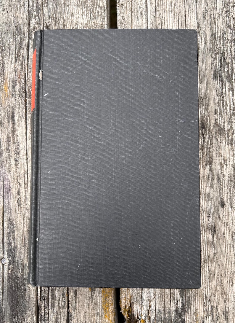 Pu&ograve; includere: Un libro con copertina rigida rettangolare rivestito in tessuto nero. Il dorso del libro presenta una piccola striscia decorativa rossa verticale vicino al bordo superiore. La superficie della copertina mostra lievi segni di usura.