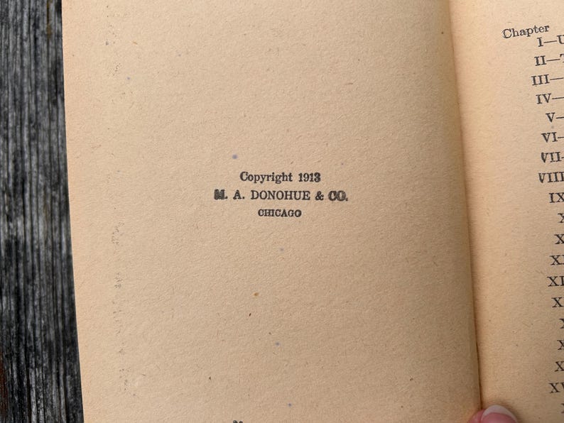 K&ouml;nnte beinhalten: Eine Seite aus einem antiken Buch mit hellbeigem Papier. Der Text lautet Copyright 1913, M. A. Donohue & Co., Chicago. Rechts ist eine teilweise Kapitel&uuml;bersicht zu sehen, beginnend mit Kapitel I bis XV in r&ouml;mischen Ziffern.