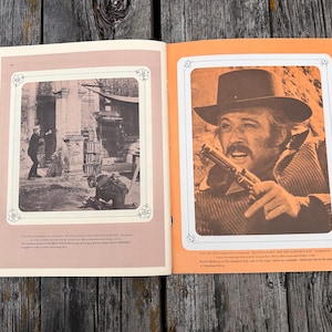 K&ouml;nnte beinhalten: Eine Vintage-Magazinseite mit zwei Schwarz-Wei&szlig;-Filmszenen aus Butch Cassidy und Sundance Kid. Die linke Seite zeigt eine Szene mit zwei Figuren, w&auml;hrend die rechte Seite eine Nahaufnahme eines Mannes mit Cowboyhut zeigt, der einen Revolver h&auml;lt.