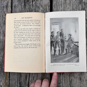 May include: An open book titled Roy Blakeley with a page of printed text on the left and a black and white illustration on the right. The illustration depicts four figures on a staircase with the caption, "Here, read this letter," said Pee-wee to Roy.