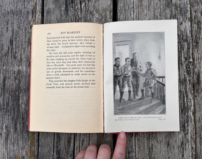 May include: An open book titled Roy Blakeley with a page of printed text on the left and a black and white illustration on the right. The illustration depicts four figures on a staircase with the caption, "Here, read this letter," said Pee-wee to Roy.
