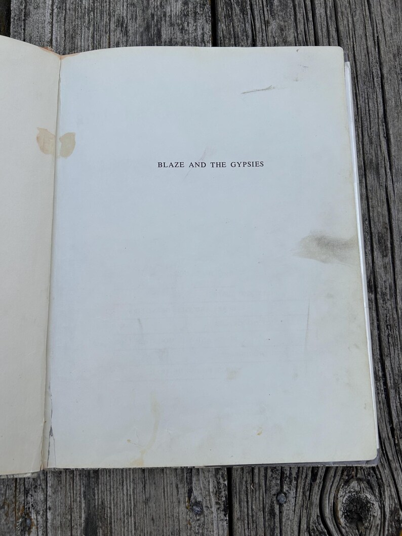 May include: The title page of a book with the text BLAZE AND THE GYPSIES printed in black ink in the center. The off-white paper shows visible signs of age, including light brown staining and discoloration spots along the left and right edges.