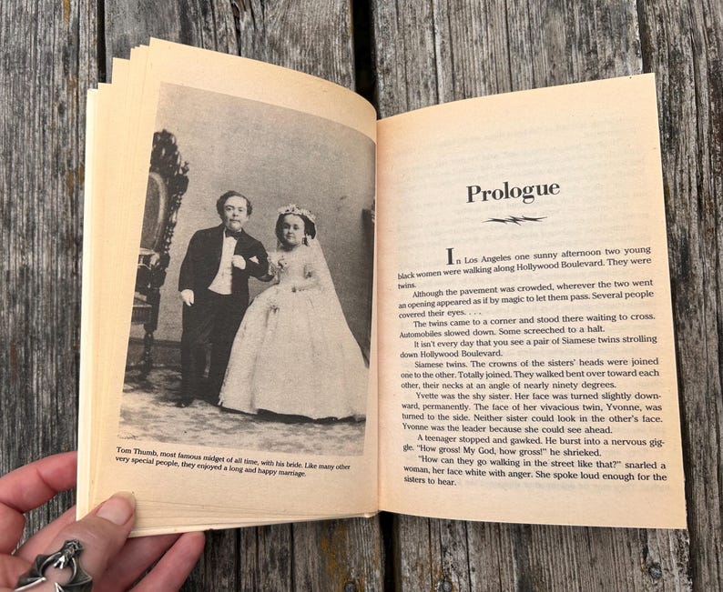 Pu&ograve; includere: Un libro aperto con pagine color crema. La pagina sinistra presenta una fotografia in bianco e nero di una persona in smoking accanto a una persona in abito da sposa. La pagina destra contiene testo sotto il titolo Prologue.