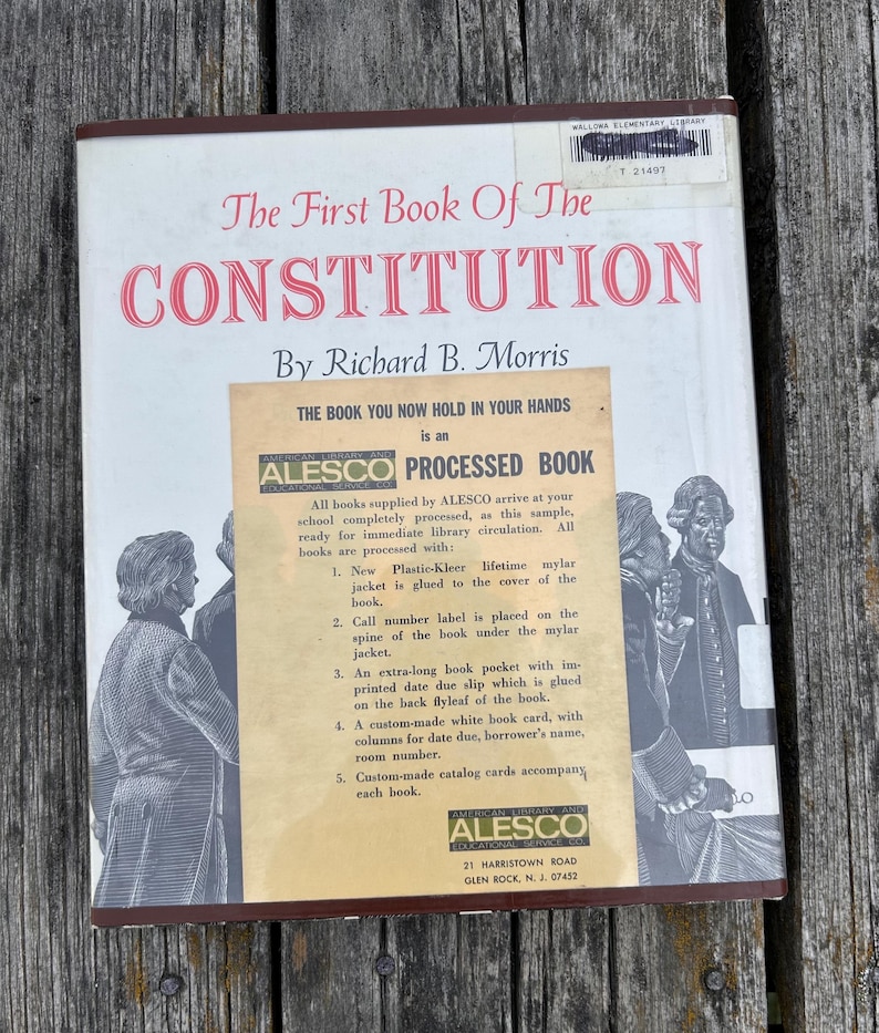 Puede incluir: Un libro de tapa dura titulado The First Book Of The Constitution de Richard B. Morris. La cubierta blanca presenta ilustraciones en blanco y negro de figuras hist&oacute;ricas y una pegatina beige de Alesco.