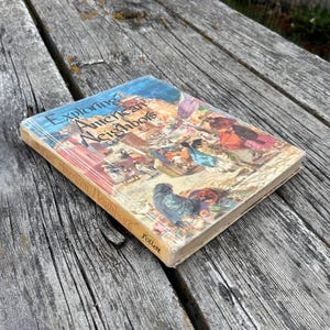 Może przedstawiać: Książka w twardej oprawie zatytułowana Exploring American Neighbors wydana przez Follett. Okładka zawiera kolorową ilustrację postaci historycznych i krajobraz&oacute;w. Książka jest ustawiona pod kątem, ukazując przednią okładkę i grzbiet.