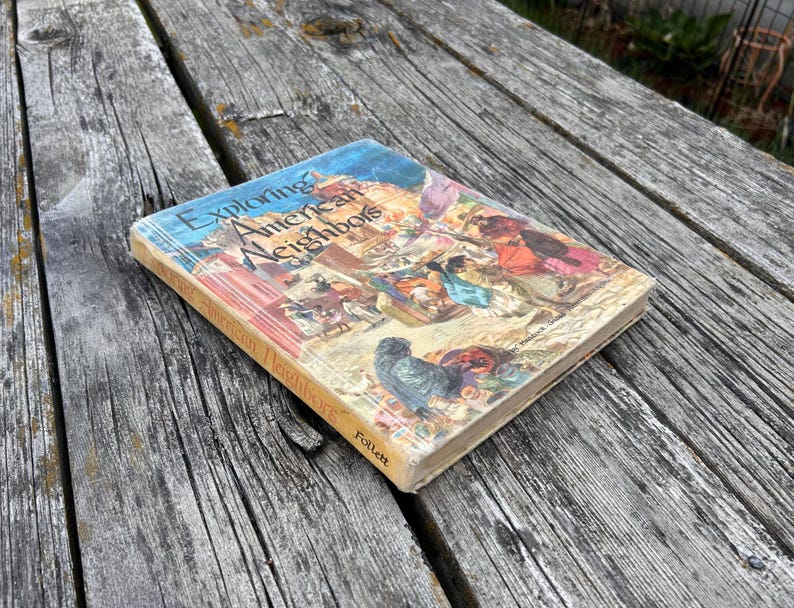 Może przedstawiać: Książka w twardej oprawie zatytułowana Exploring American Neighbors wydana przez Follett. Okładka zawiera kolorową ilustrację postaci historycznych i krajobraz&oacute;w. Książka jest ustawiona pod kątem, ukazując przednią okładkę i grzbiet.
