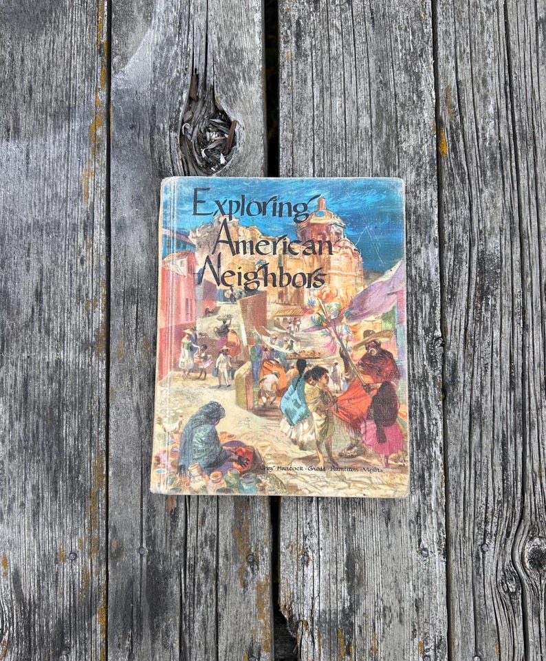 Może przedstawiać: Książka w twardej oprawie zatytułowana Exploring American Neighbors z kolorową ilustracją na okładce przedstawiającą tętniący życiem targ na świeżym powietrzu z ludźmi w tradycyjnych strojach, budynkami i dużą kopułą w tle.