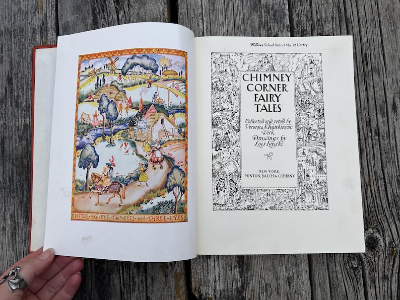 May include: An open hardcover book titled Chimney Corner Fairy Tales, collected by Veronica S. Hutchinson with drawings by Lois Lenski. The left page features a colorful illustration of a rural landscape, while the right page displays the title text.