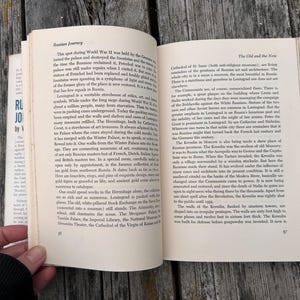 May include: An open hardback book titled Russian Journey with two pages of black printed text visible. The left page is headed Russian Journey and the right page is headed The Old and the New, with page numbers 56 and 57 at the bottom corners.