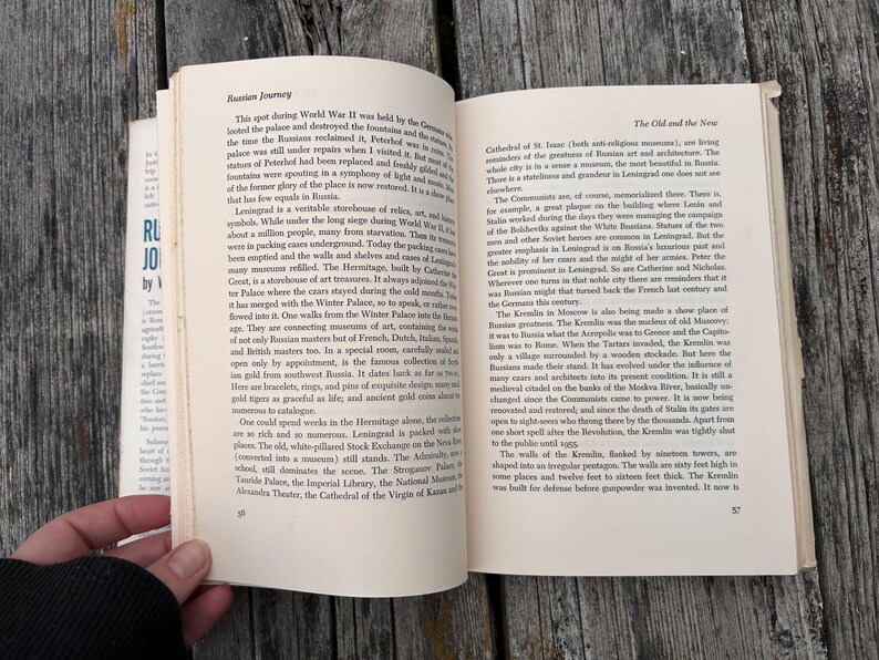 May include: An open hardback book titled Russian Journey with two pages of black printed text visible. The left page is headed Russian Journey and the right page is headed The Old and the New, with page numbers 56 and 57 at the bottom corners.