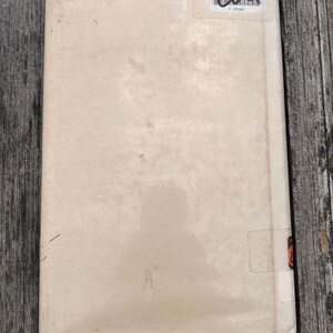 Puede incluir: Una cubierta de libro rectangular de color blanco roto con un acabado mate y liso. En la esquina superior derecha, una etiqueta de biblioteca rectangular blanca presenta un c&oacute;digo de barras negro y el texto Wallowa Elementary Library.