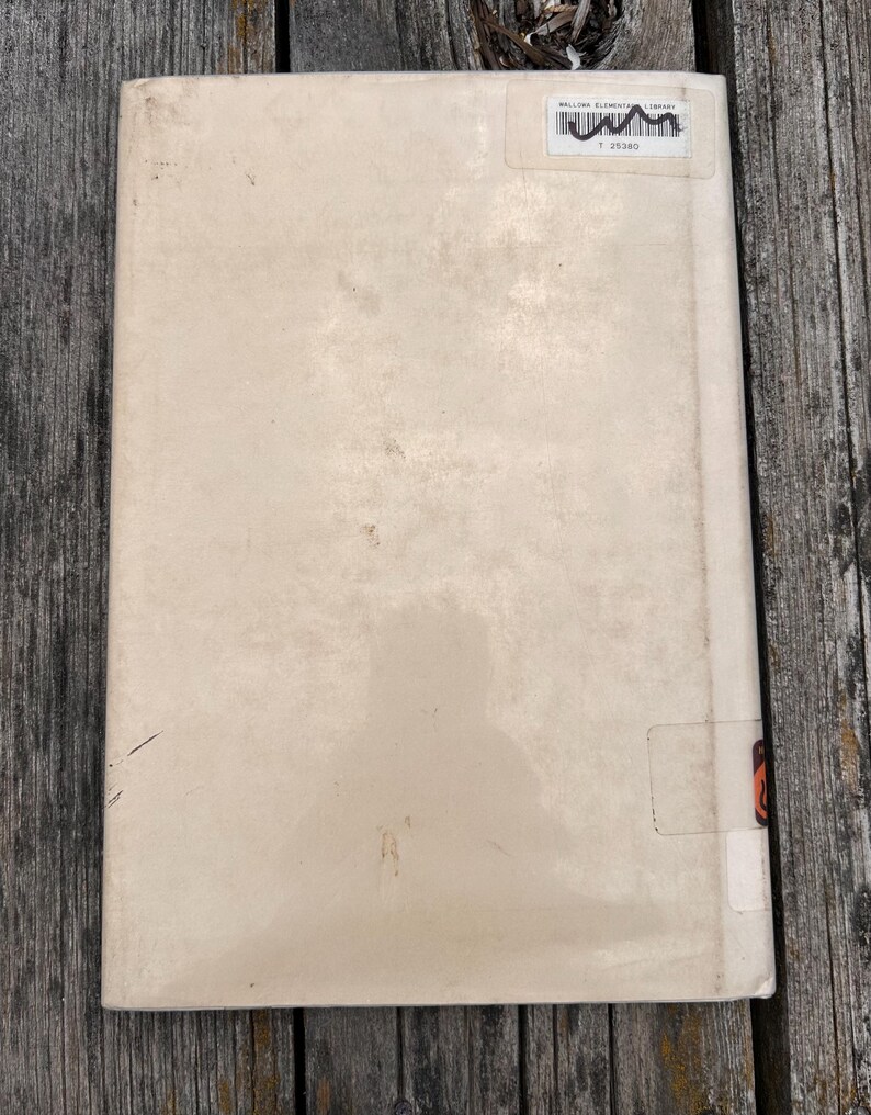 Puede incluir: Una cubierta de libro rectangular de color blanco roto con un acabado mate y liso. En la esquina superior derecha, una etiqueta de biblioteca rectangular blanca presenta un c&oacute;digo de barras negro y el texto Wallowa Elementary Library.
