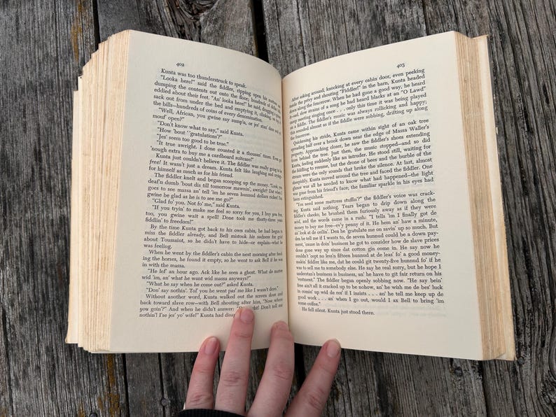 K&ouml;nnte beinhalten: Ein aufgeschlagenes Hardcover-Buch mit cremefarbenen Seiten und schwarzem Drucktext. Die linke Seite ist mit 402 und die rechte Seite mit 403 nummeriert. Das Buch ist mit sichtbarer Bindung und R&auml;ndern dargestellt und zeigt dichte Abs&auml;tze mit Erz&auml;hltext.