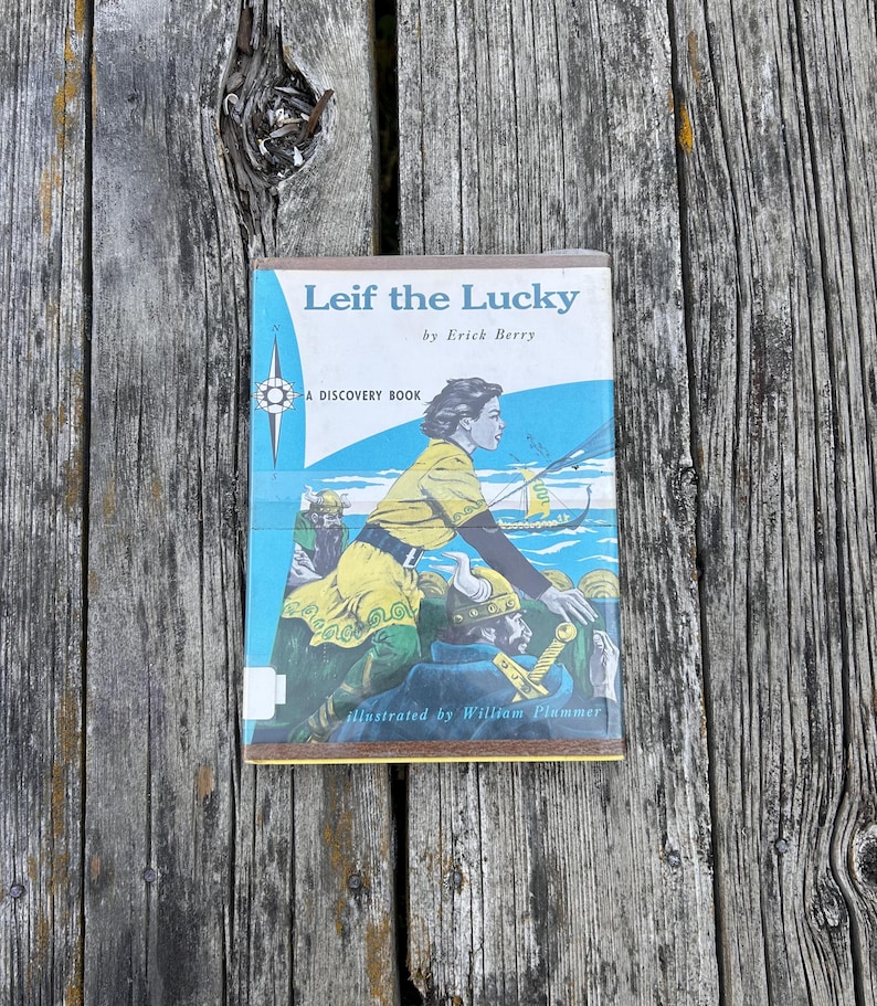 Pu&ograve; includere: Un libro con copertina rigida intitolato Leif the Lucky di Erick Berry, illustrato da William Plummer. La copertina presenta uno sfondo blu con una figura vestita di giallo, una nave vichinga e una grafica a rosa dei venti. &Egrave; un'edizione Discovery Book.