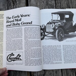 Op de afbeelding: Een open boekpagina met een zwart-witfoto van een 1914 Series H Royal Mail roadster. De tekst bevat de titel The Early Years: Royal Mail and Baby Grand, een Chevrolet-logo en kolommen met historische informatie over auto's.
