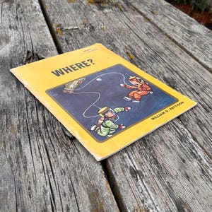 May include: A yellow softcover book titled WHERE? by William D. Pattison. The cover features a dark blue rectangular illustration of two astronauts in orange and green suits floating in space, connected by a tether to a small spacecraft.