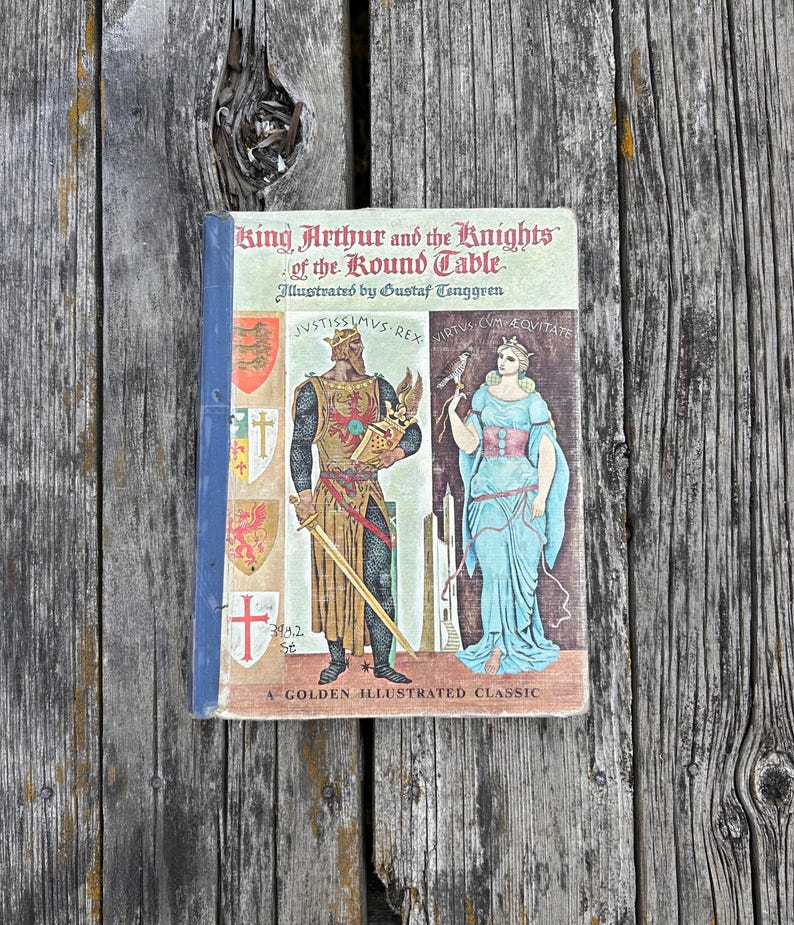 Może przedstawiać: Książka w twardej oprawie zatytułowana King Arthur and the Knights of the Round Table, z ilustracjami Gustafa Tenggrena. Okładka przedstawia rycerza w zbroi i kobietę w niebieskiej sukni, z herbami oraz napisem A Golden Illustrated Classic.