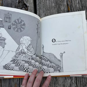 May include: An open illustrated book featuring a black and white line drawing of a child sitting in bed with a quilt. The text on the right page reads: "Onc't they was a little boy wouldn't say his prayers-". The illustration shows a bedroom scene.