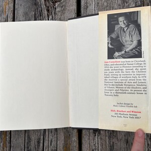 May include: An open hardcover book with a cream-colored page on the left and a dust jacket flap on the right. The flap features a black and white portrait of Ann Cornelisen above a biography and publisher information for Holt, Rinehart and Winston.