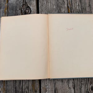 Pu&ograve; includere: Un libro aperto con pagine bianche color avorio. La pagina destra presenta una piccola iscrizione centrata in inchiostro rosso in stile manoscritto che recita "Inklings". Il libro ha una copertina grigia ed &egrave; disposto in piano.