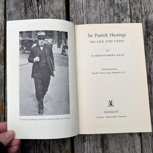 Pu&ograve; includere: Un libro con copertina rigida intitolato Sir Patrick Hastings: His Life and Cases di H. Montgomery Hyde. La pagina sinistra presenta una fotografia in bianco e nero di un uomo in abito e cappello che cammina, con la didascalia Sir Patrick Hastings.