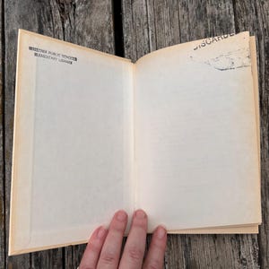 Pu&ograve; includere: Un libro con copertina rigida aperto con pagine color crema. La pagina sinistra presenta un timbro a inchiostro nero con la scritta WALLOWA PUBLIC SCHOOL ELEMENTARY LIBRARY. La pagina destra ha un timbro nero nell'angolo in alto a destra con la scritta DISCARDED.