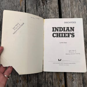 Może przedstawiać: Otwarta książka pod tytułem Indian Chiefs autorstwa Lynne Deur, wydana przez Lear Siegler, Inc./Fearon Publishers. Na wewnętrznej stronie okładki znajduje się pieczątka ESEA Title II Property of Wallowa School District oraz nadrukowane słowo DISCARDED.