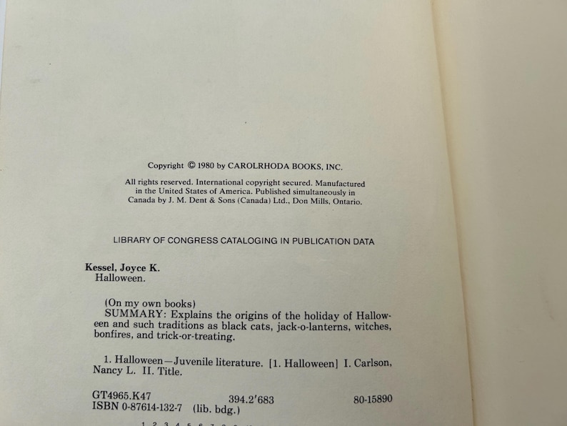 Może przedstawiać: Kremowa strona praw autorskich książki z czarnym drukowanym tekstem. Zawiera informację o prawach autorskich dla Carolrhoda Books, Inc. 1980, dane katalogowe Biblioteki Kongresu oraz streszczenie książki Halloween autorstwa Joyce K. Kessel.