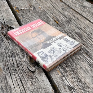 Puede incluir: Un libro de tapa dura titulado Famous American Indians de William Heuman. La portada presenta un gran retrato de un hombre e ilustraciones m&aacute;s peque&ntilde;as en blanco y negro de varios individuos. El libro tiene un lomo rojo y una cubierta beige y blanca.