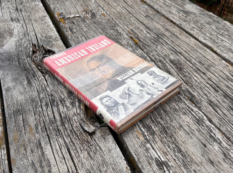 Puede incluir: Un libro de tapa dura titulado Famous American Indians de William Heuman. La portada presenta un gran retrato de un hombre e ilustraciones m&aacute;s peque&ntilde;as en blanco y negro de varios individuos. El libro tiene un lomo rojo y una cubierta beige y blanca.