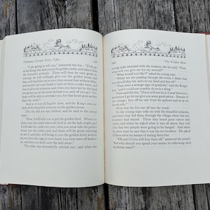 May include: An open hardcover book with cream-colored pages featuring black printed text and decorative illustrations at the top of each page. The left page is titled Chimney Corner Fairy Tales and the right page is titled The Golden Bird.