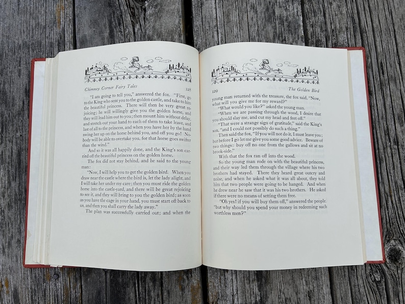 May include: An open hardcover book with cream-colored pages featuring black printed text and decorative illustrations at the top of each page. The left page is titled Chimney Corner Fairy Tales and the right page is titled The Golden Bird.