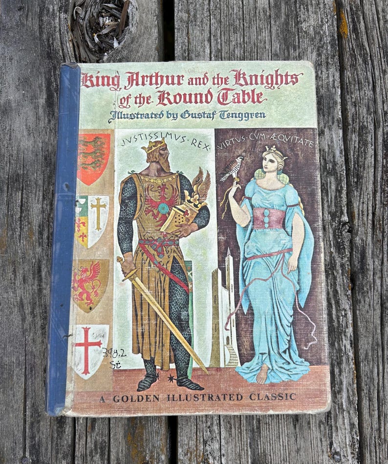 Może przedstawiać: Książka w twardej oprawie zatytułowana King Arthur and the Knights of the Round Table, z ilustracjami Gustafa Tenggrena. Okładka przedstawia kr&oacute;la z mieczem i kobietę z sokołem, obok herb&oacute;w oraz napisu A Golden Illustrated Classic.