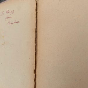 K&ouml;nnte beinhalten: Die aufgeschlagenen Seiten eines alten Buches mit gealtertem, cremefarbenem Papier. Die linke Seite zeigt handschriftlichen Tintentext mit 1955 und To Buzz from Grandma. Die rechte Seite enth&auml;lt handschriftlichen Tintentext To Albert from Har.