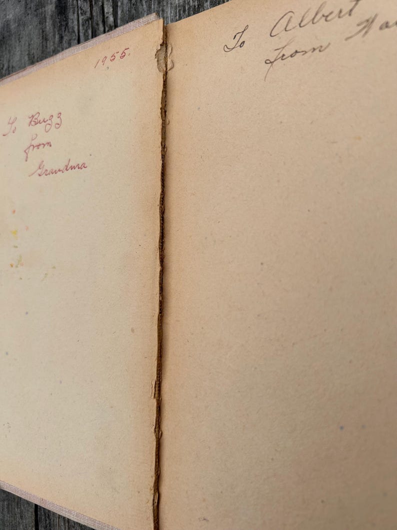 K&ouml;nnte beinhalten: Die aufgeschlagenen Seiten eines alten Buches mit gealtertem, cremefarbenem Papier. Die linke Seite zeigt handschriftlichen Tintentext mit 1955 und To Buzz from Grandma. Die rechte Seite enth&auml;lt handschriftlichen Tintentext To Albert from Har.