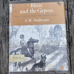 May include: A hardcover book titled Blaze and the Gypsies by C. W. Anderson, featuring the subtitle Blaze Escapes from the Horse Thieves. The cover displays a black and white illustration of a person riding a horse with a dog nearby and a wagon.