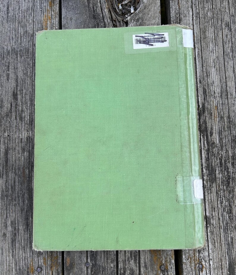 K&ouml;nnte beinhalten: Ein hellgr&uuml;nes Hardcover-Buch mit einem strukturierten Stoffeinband. Der Buchr&uuml;ckenbereich ist mit einem vertikal verlaufenden, transparenten Klebestreifen versehen. Oben befindet sich ein wei&szlig;er Bibliotheksaufkleber mit Barcode und Tinte.