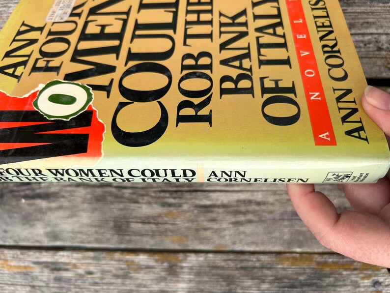 May include: A hardcover book titled Any Four Women Could Rob the Bank of Italy by Ann Cornelisen. The cover is yellow with black text and a red stripe. A circular green sticker with a white zero is partially covering the title on the front.