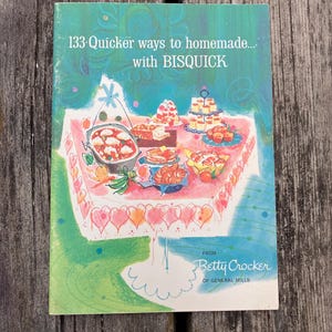 Può includere: Una copertina di libro di cucina vintage con il titolo "133 modi più veloci per fare in casa... con BISQUICK". La copertina presenta un'illustrazione di un tavolo imbandito con vari piatti. Il logo Betty Crocker è visibile.