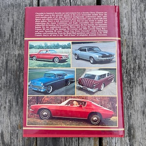 Op de afbeelding: Een hardcover boek getiteld Great Cars From Chevrolet met een dieprode kaft. De achterkant bevat een beschrijvende tekst over de geschiedenis van Chevrolet en vijf kleurenfoto's van oldtimers, waaronder een rode coup&eacute; en een stationwagen.