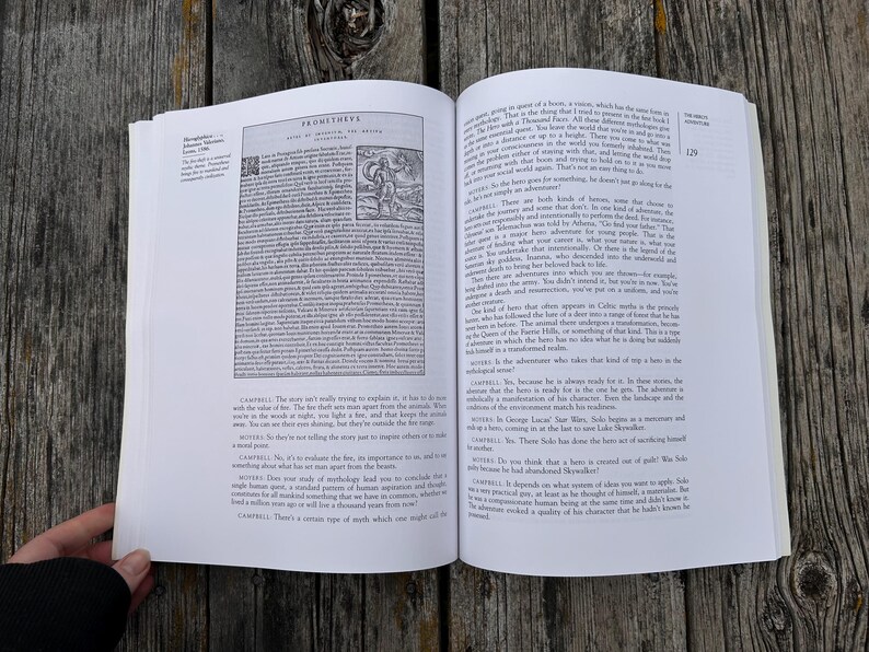 K&ouml;nnte beinhalten: Ein aufgeschlagenes Buch mit wei&szlig;en Seiten und schwarzem Drucktext. Die linke Seite zeigt einen Abschnitt mit dem Titel Prometheus und eine kleine schwarz-wei&szlig;e Abbildung einer Figur. Die rechte Seite enth&auml;lt nummerierten Text und Dialoge.