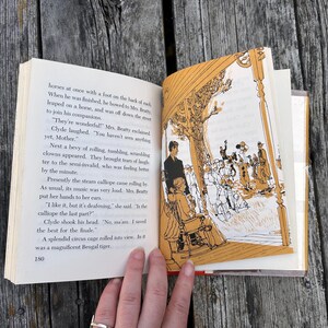 May include: An open book with black text on the left page and a monochromatic orange and white illustration on the right page. The illustration depicts a scene with figures under a structure, and the text includes the page number 180.