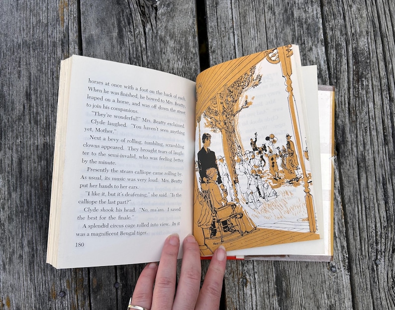 May include: An open book with black text on the left page and a monochromatic orange and white illustration on the right page. The illustration depicts a scene with figures under a structure, and the text includes the page number 180.