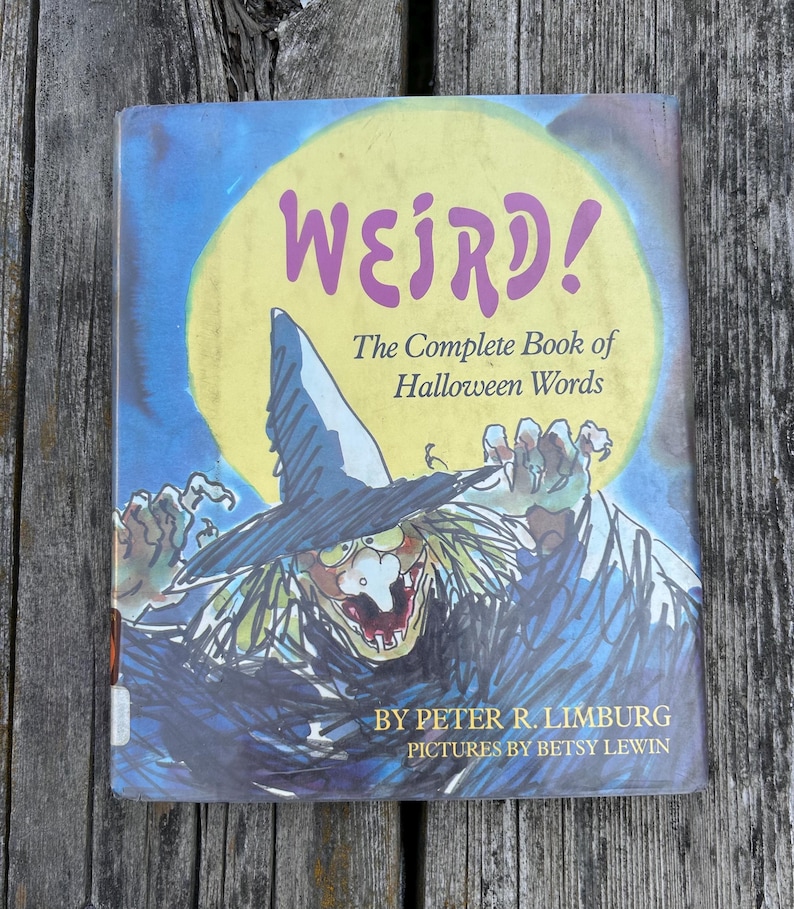 以下が含まれることがあります： ピーター・R・リンバーグ著、ベッツィ・リューイン絵のハードカバー本『WEIRD! The Complete Book of Halloween Words』。表紙には、大きな黄色い月を背景に、とんがり帽子をかぶった魔女のカラフルなイラストが描かれています。